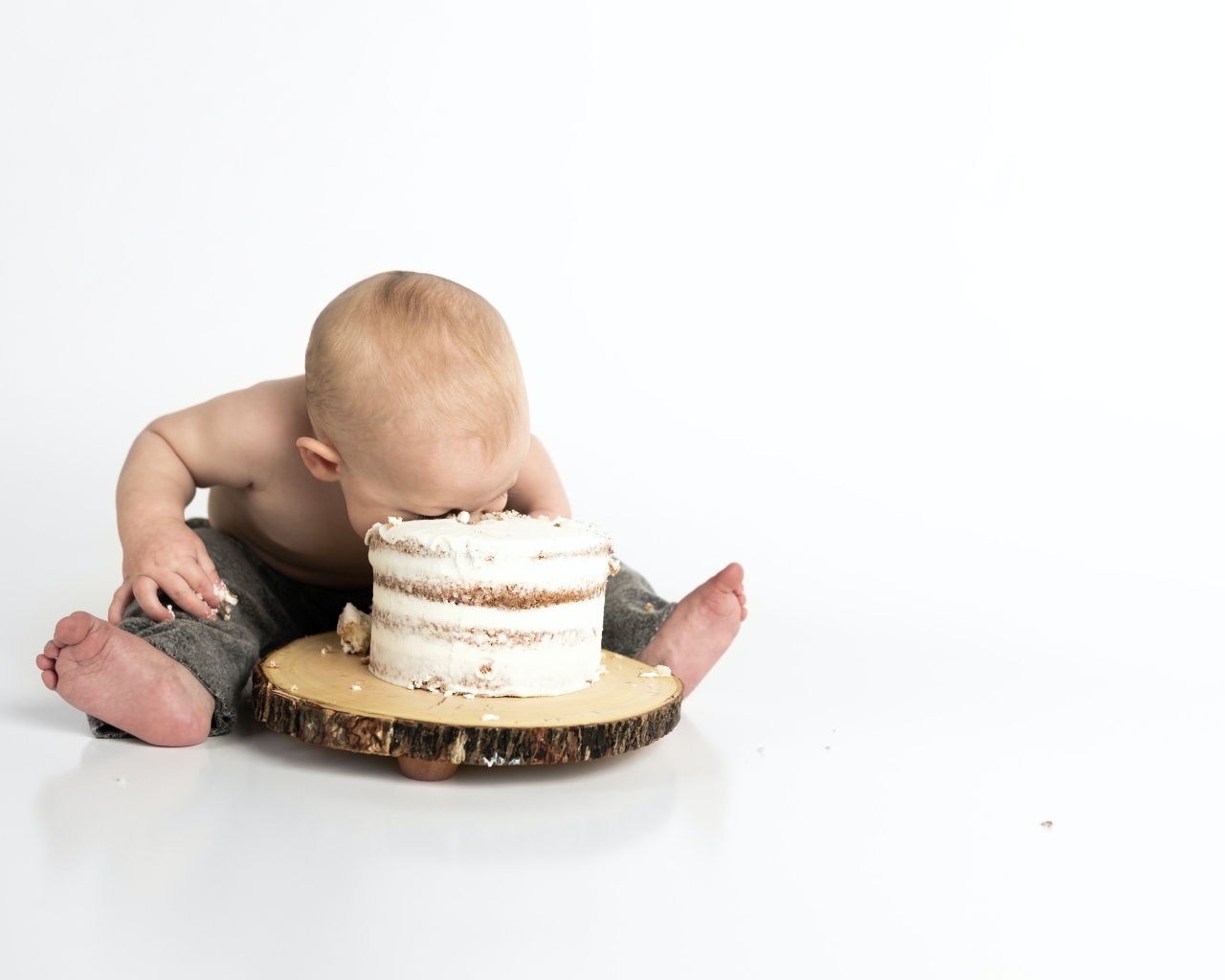 Маленький мальчик ест праздничный торт на белом фоне