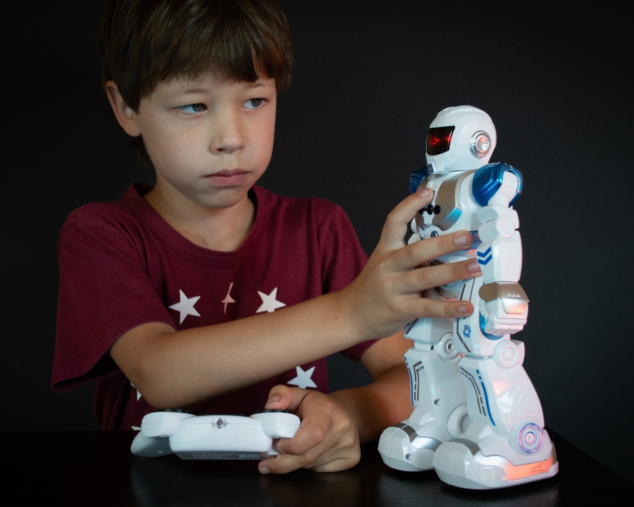 Маленький мальчик с роботом на черном фоне