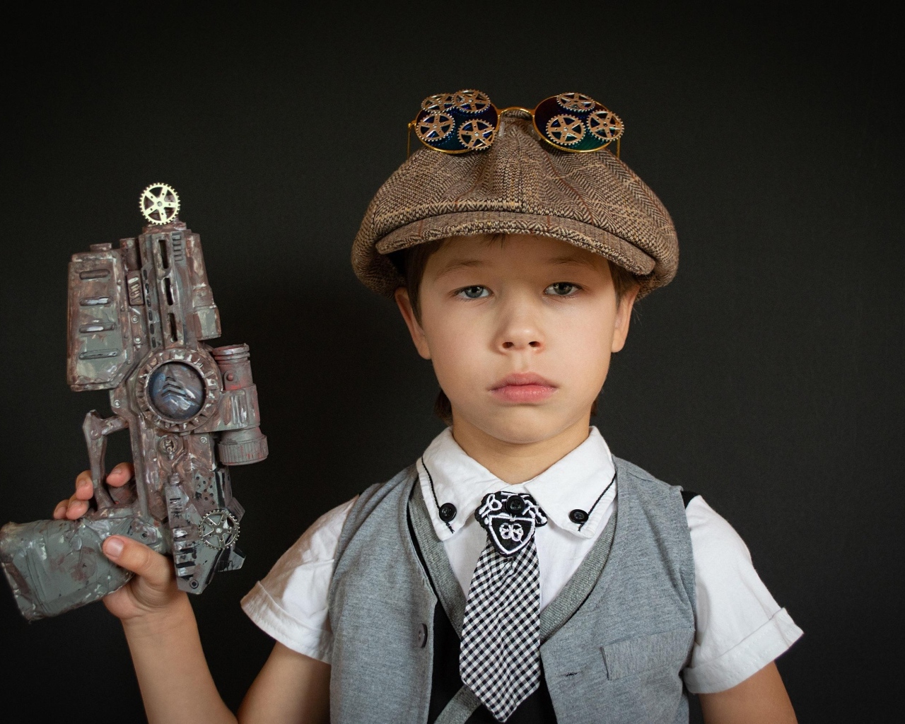 Маленький мальчик с игрушечным пистолетом на черном фоне