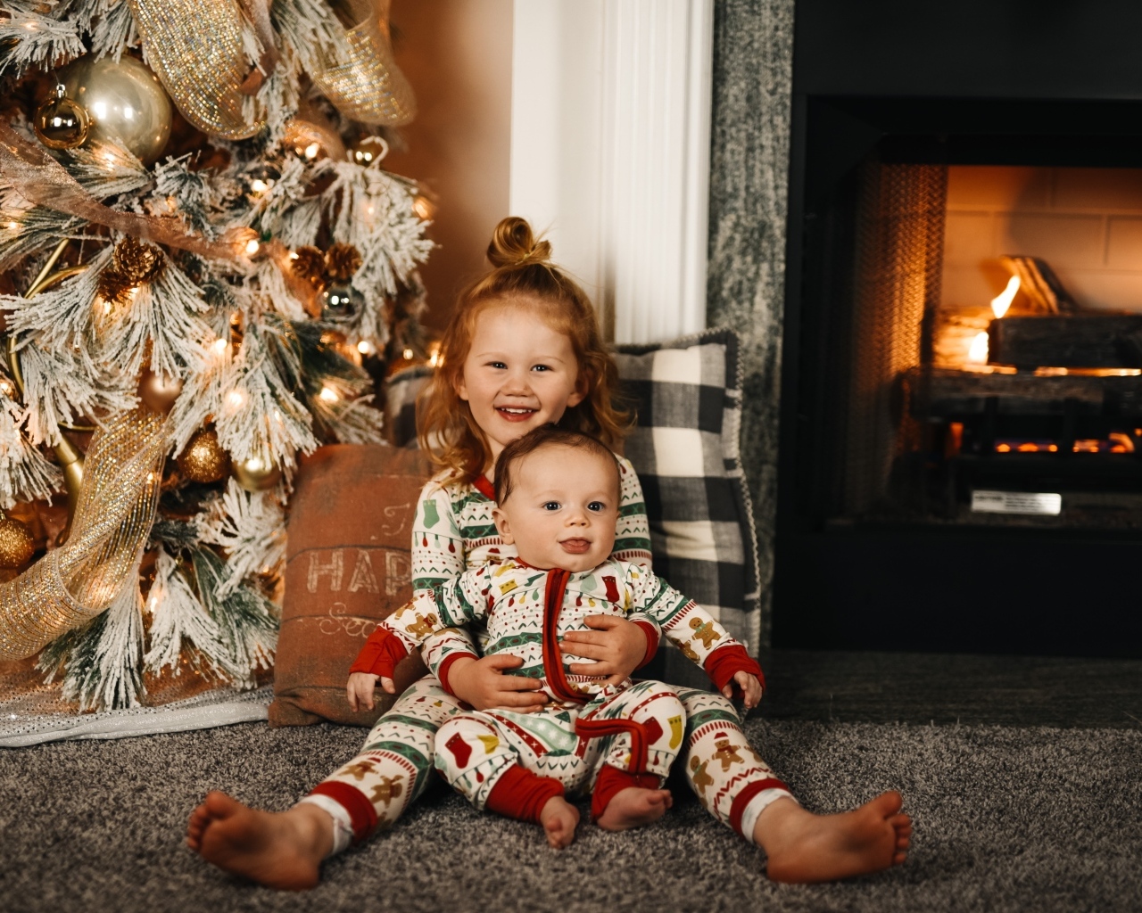 Маленькие брат и сестра сидят у новогодней ели