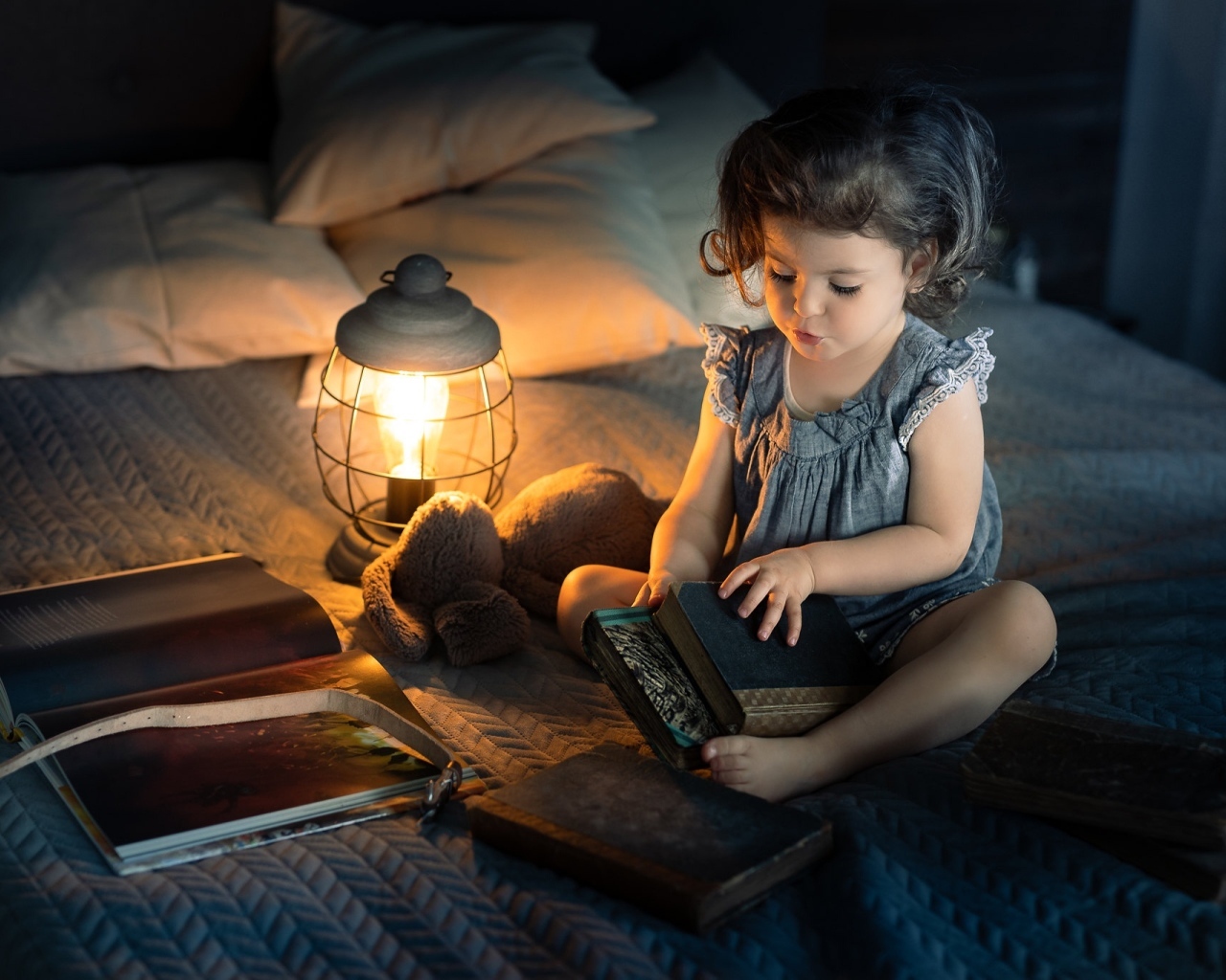 Маленькая девочка читает книги на кровати