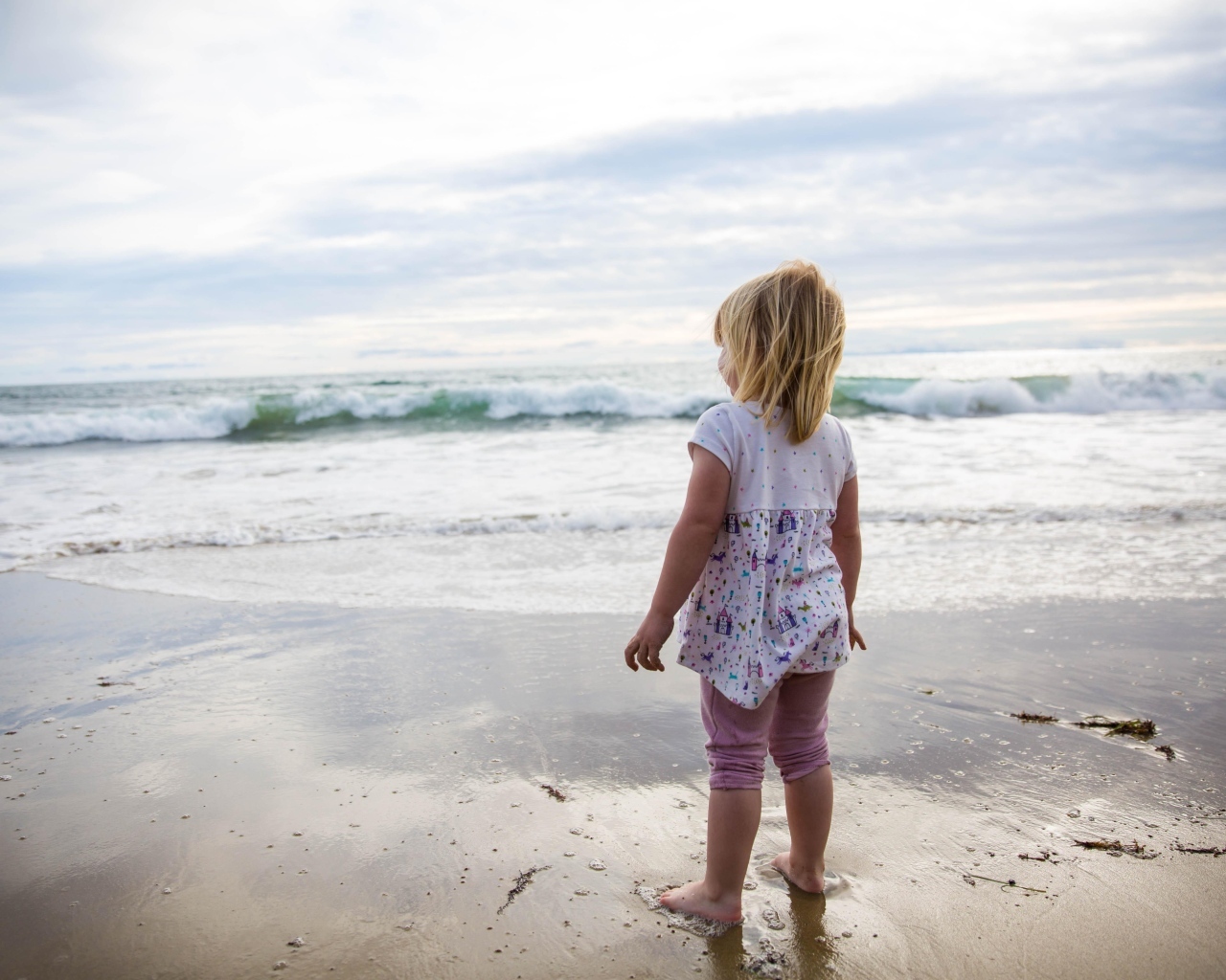 Маленькая девочка стоит на берегу моря