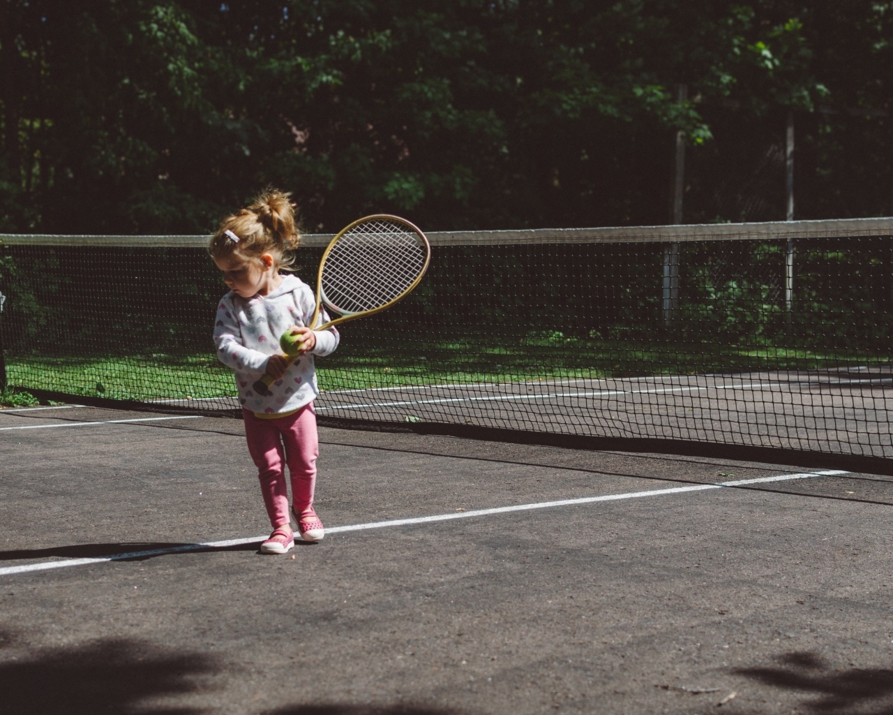 Маленькая девочка с ракеткой на поле