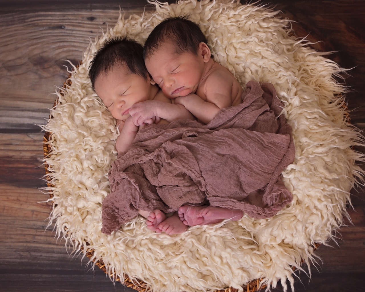 Маленькие новорожденные близнецы на меховой подушке