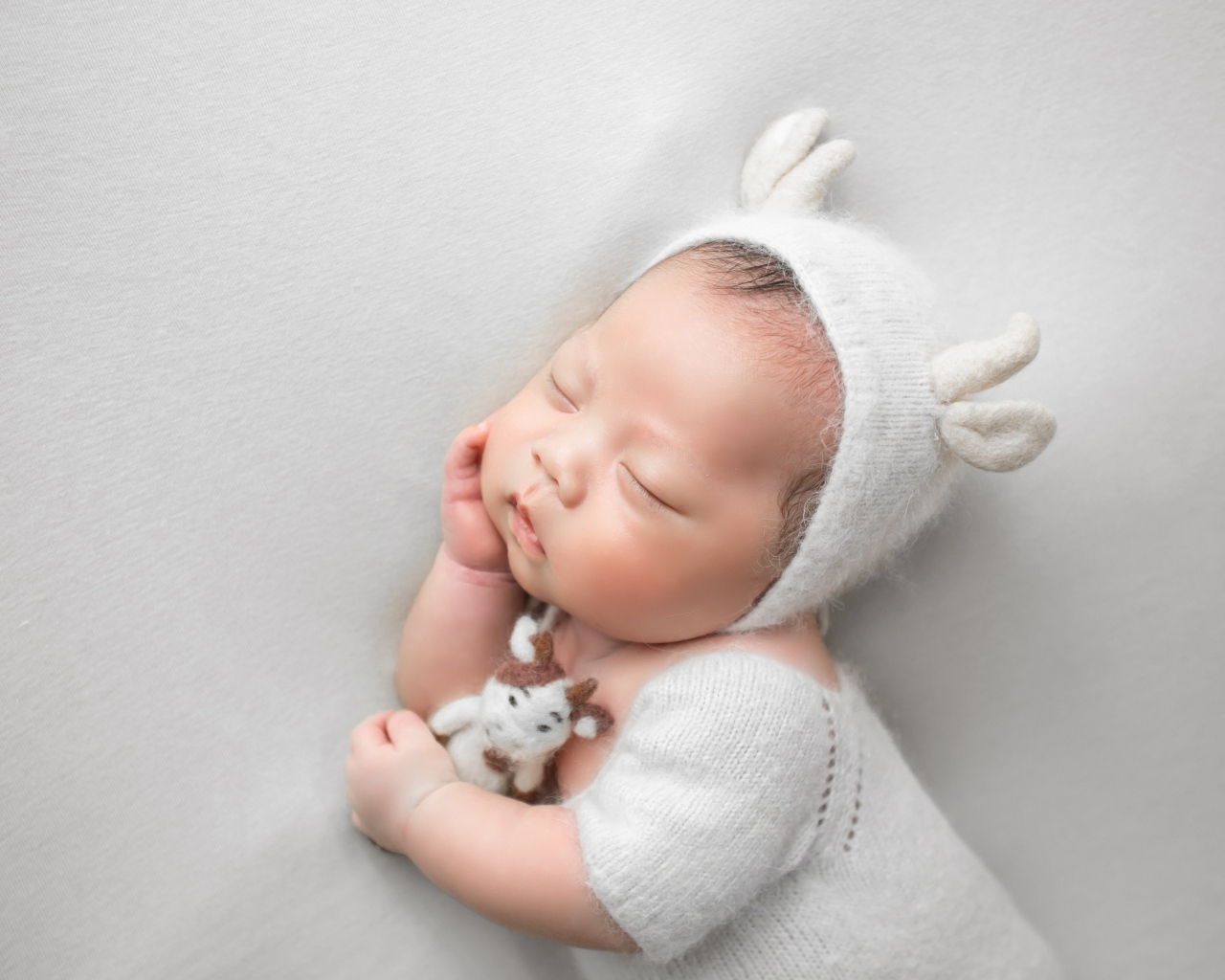 Маленький спящий малыш на сером фоне