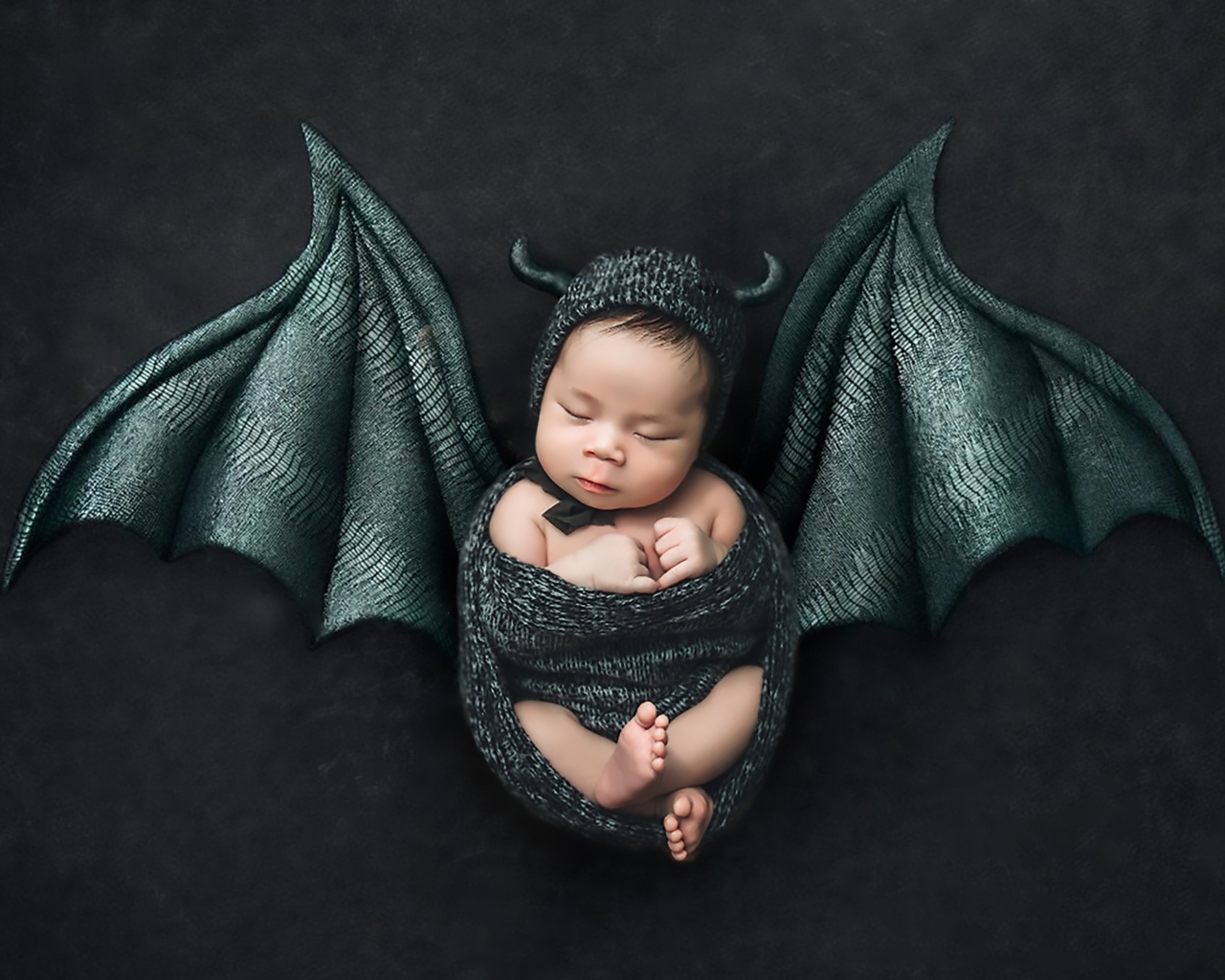 Маленький спящий ребенок с крыльями на Хэллоуин