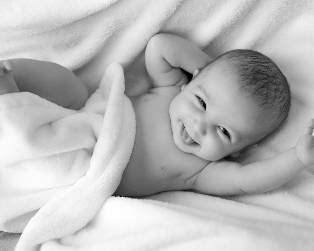 Маленький улыбающийся ребенок в белом покрывале