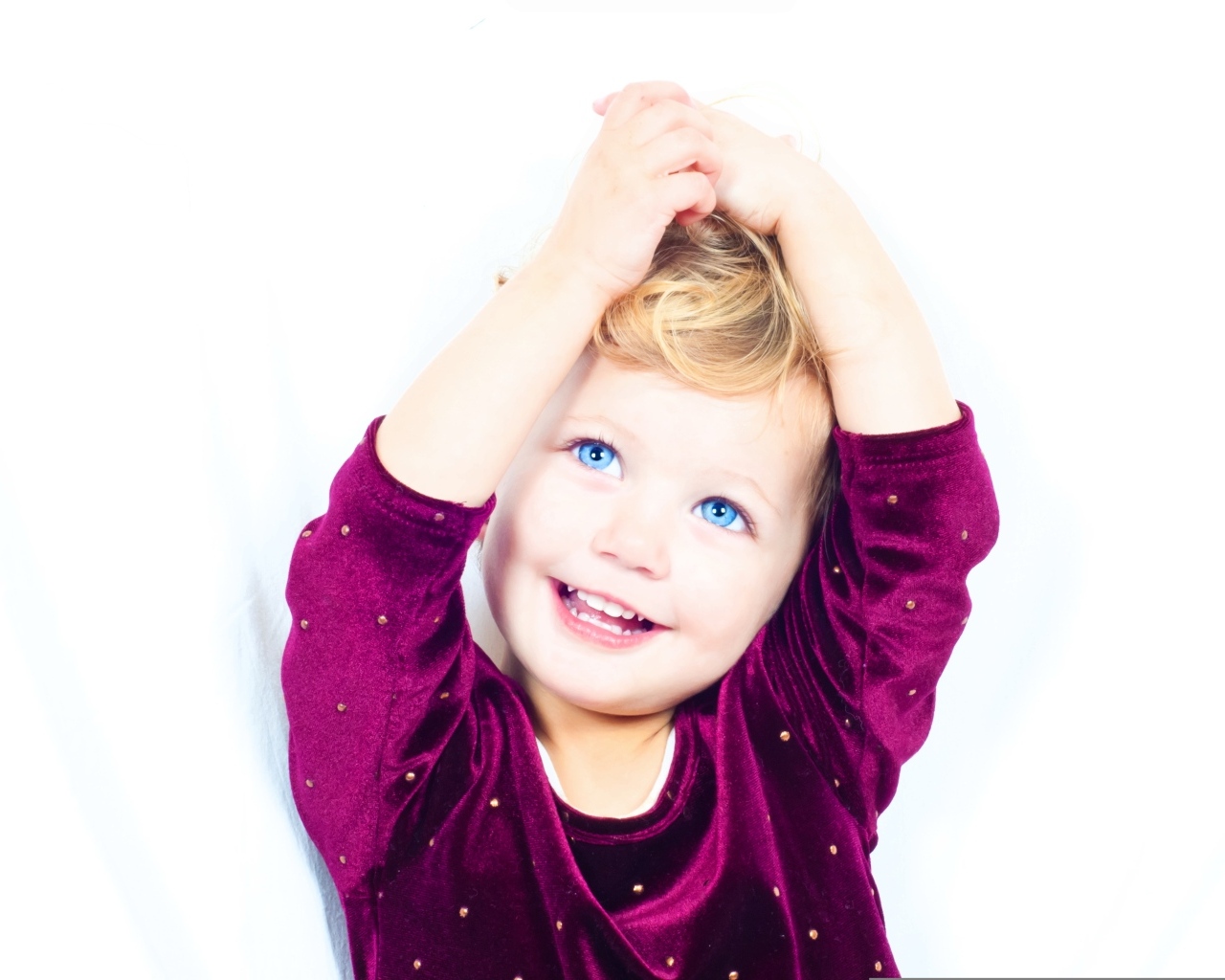 Маленькая улыбающаяся голубоглазая девочка на белом фоне