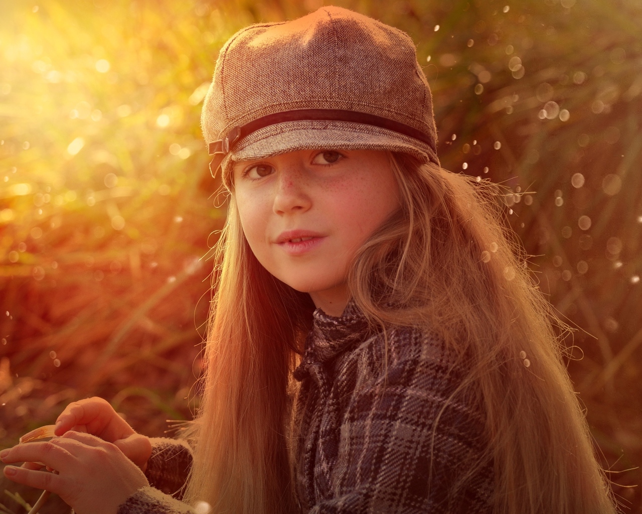 Длинноволосая девочка в кепке в лучах солнца