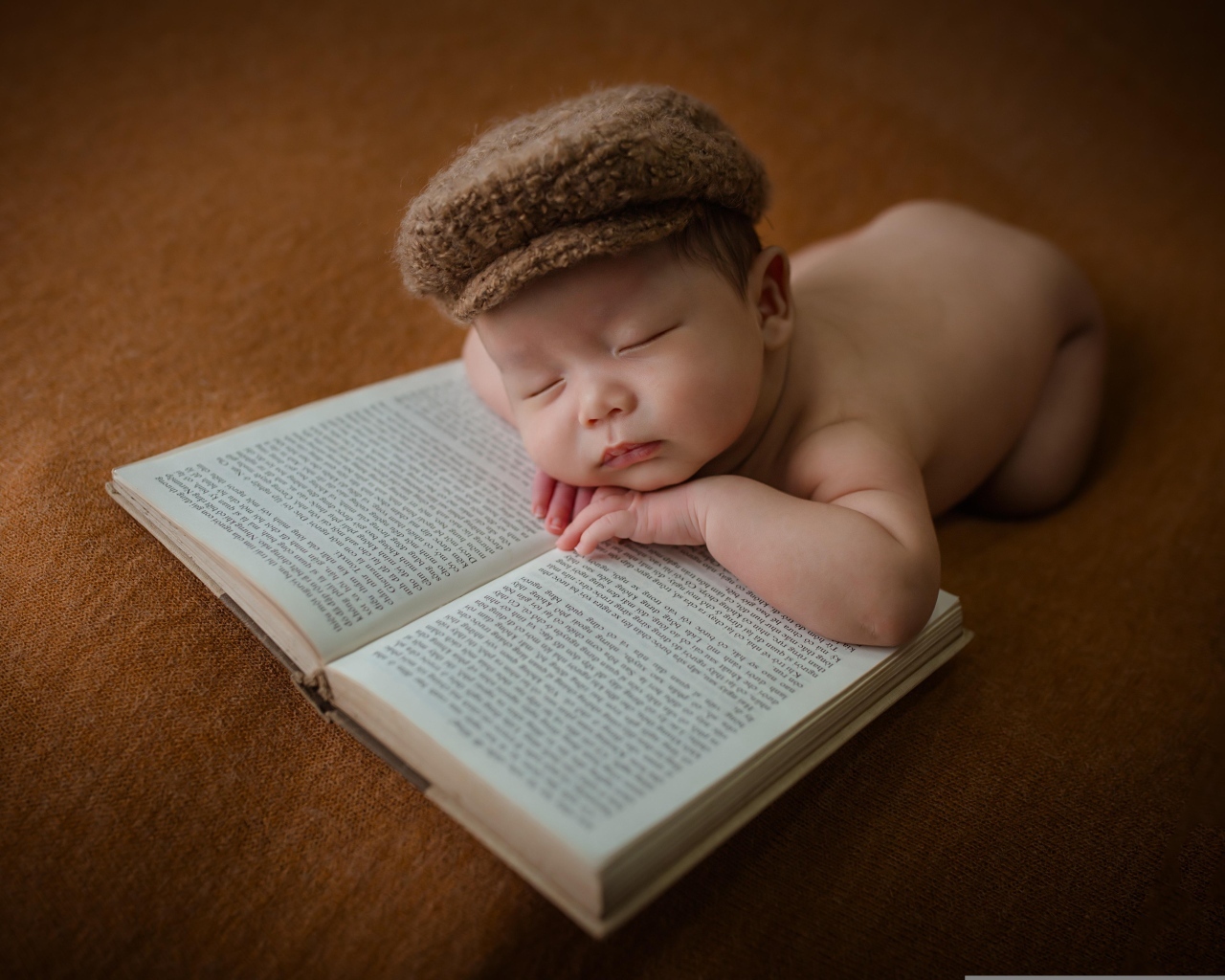 Новорожденный малыш спит на книге