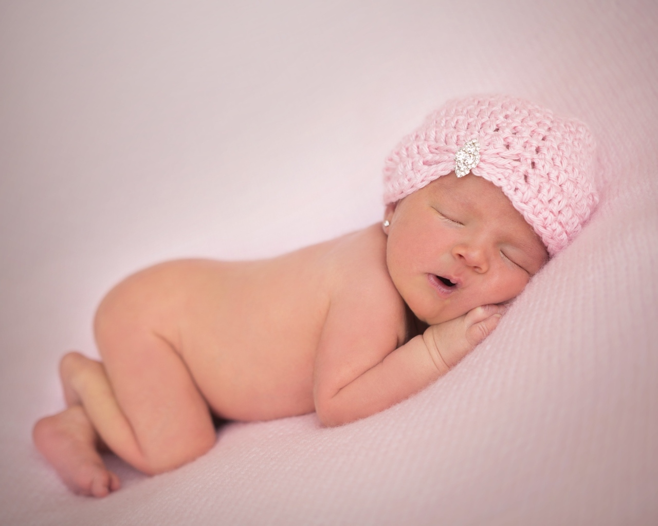 Розовая шапка на голове новорожденной девочки