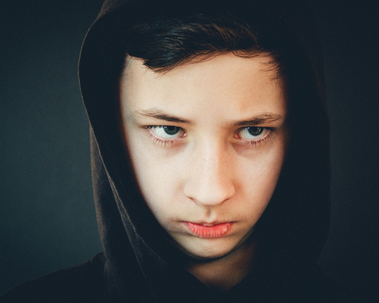 Серьезный мальчик в черном капюшоне