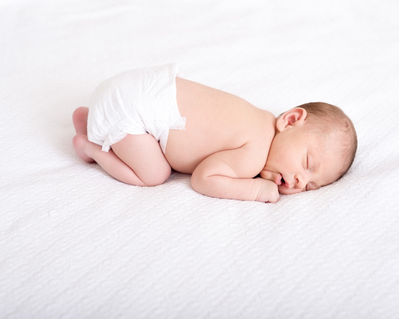 Спящий новорожденный ребенок в памперсе
