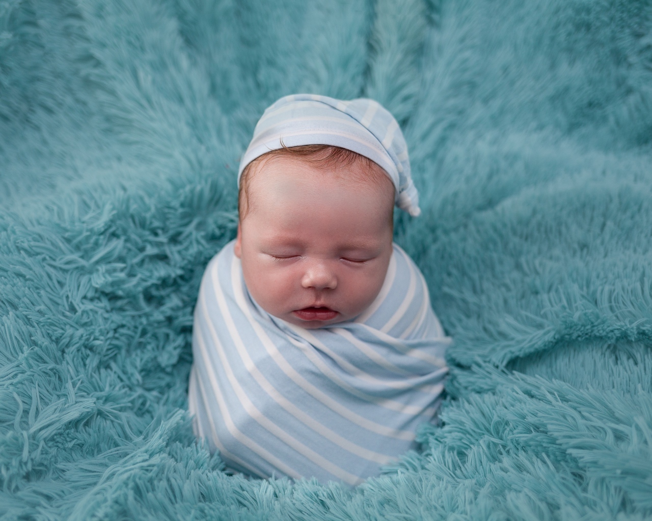 Спящий новорожденный малыш на голубом покрывале 