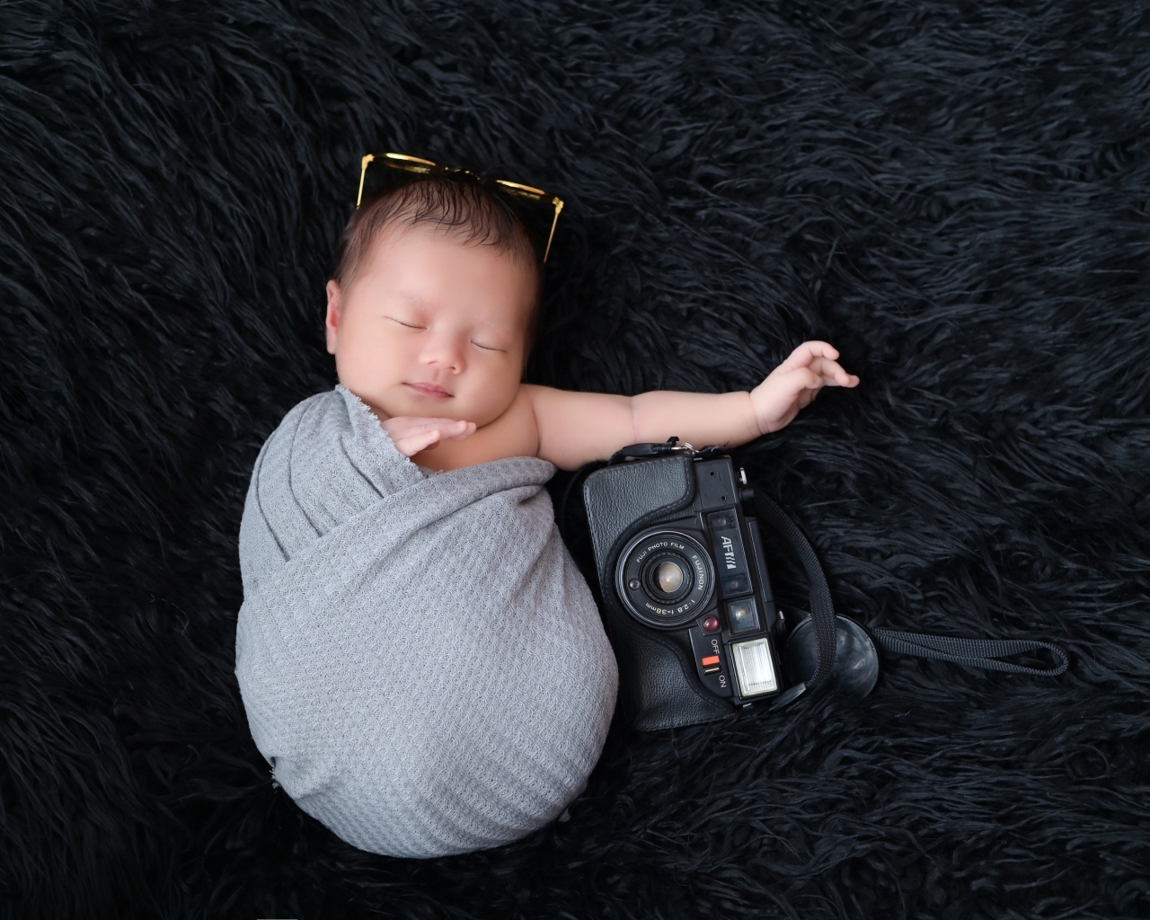 Спящий новорожденный малыш с фотоаппаратом