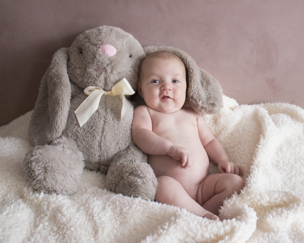 Улыбающийся малыш с игрушечным зайцем