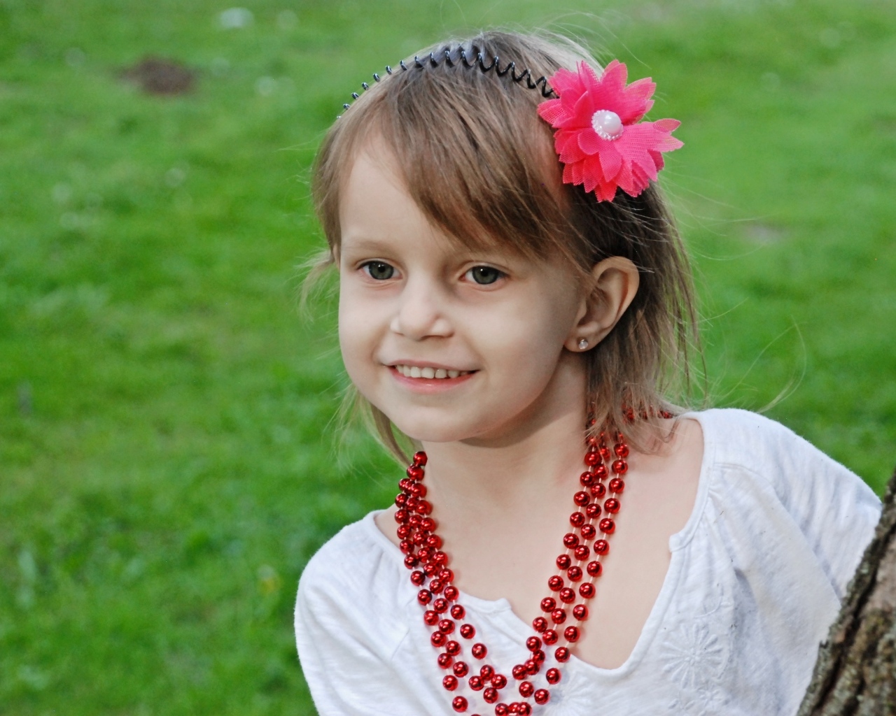 Улыбающаяся девочка стоит у дерева