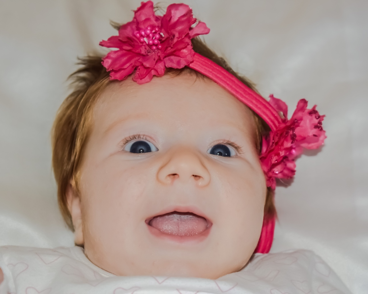 Улыбающаяся маленькая девочка с цветком на голове