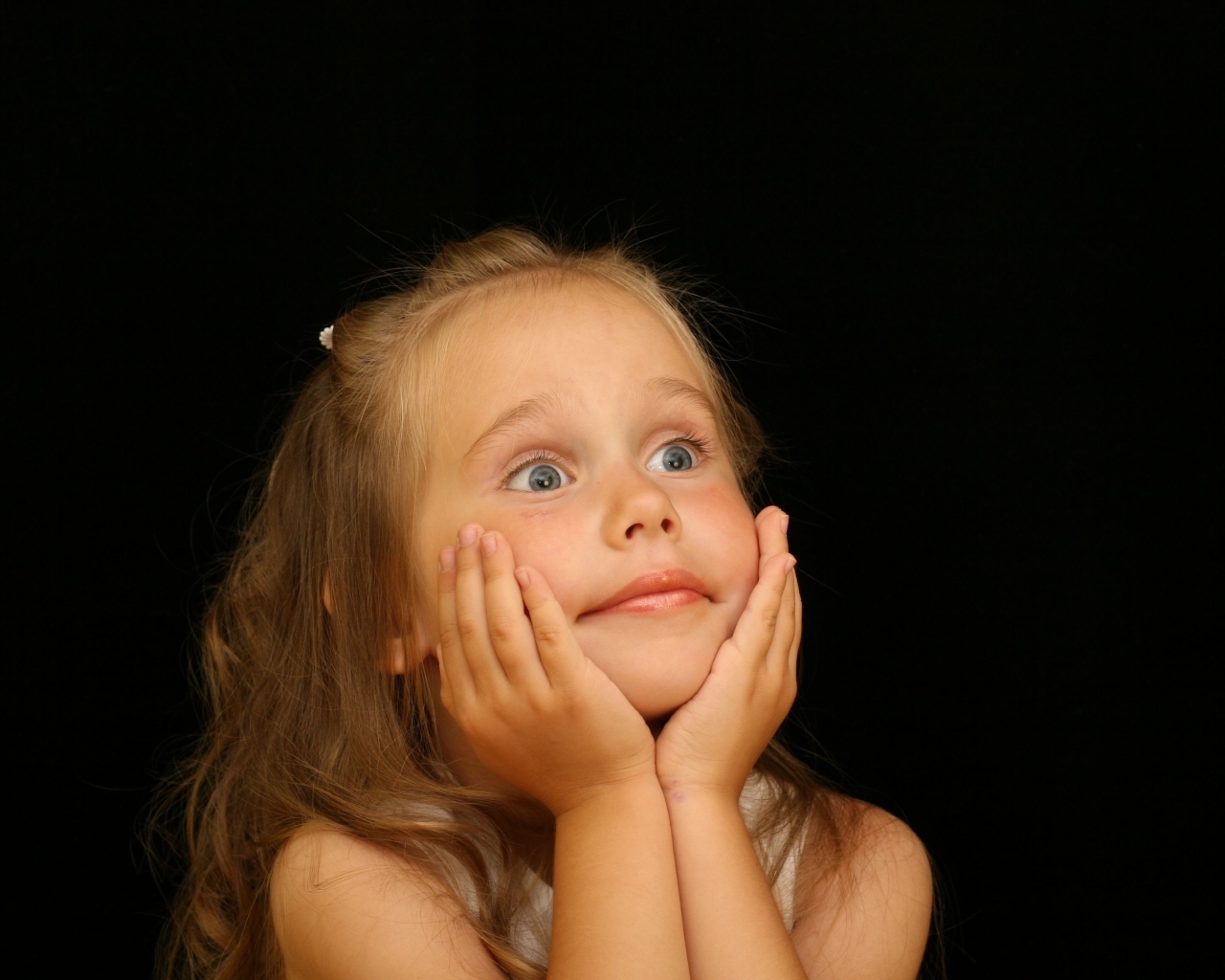 Удивленная маленькая девочка на черном фоне