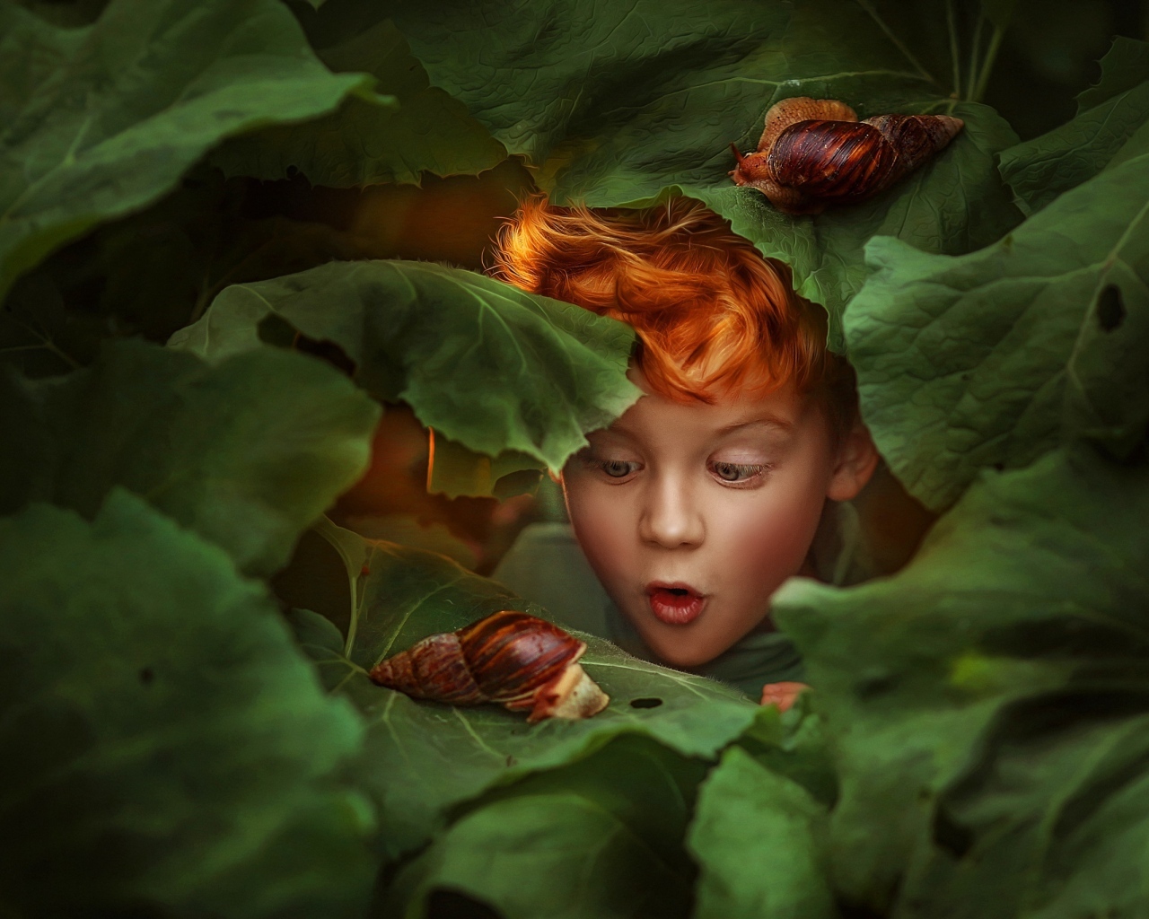 Удивленный рыжеволосый мальчик смотрит на улитку