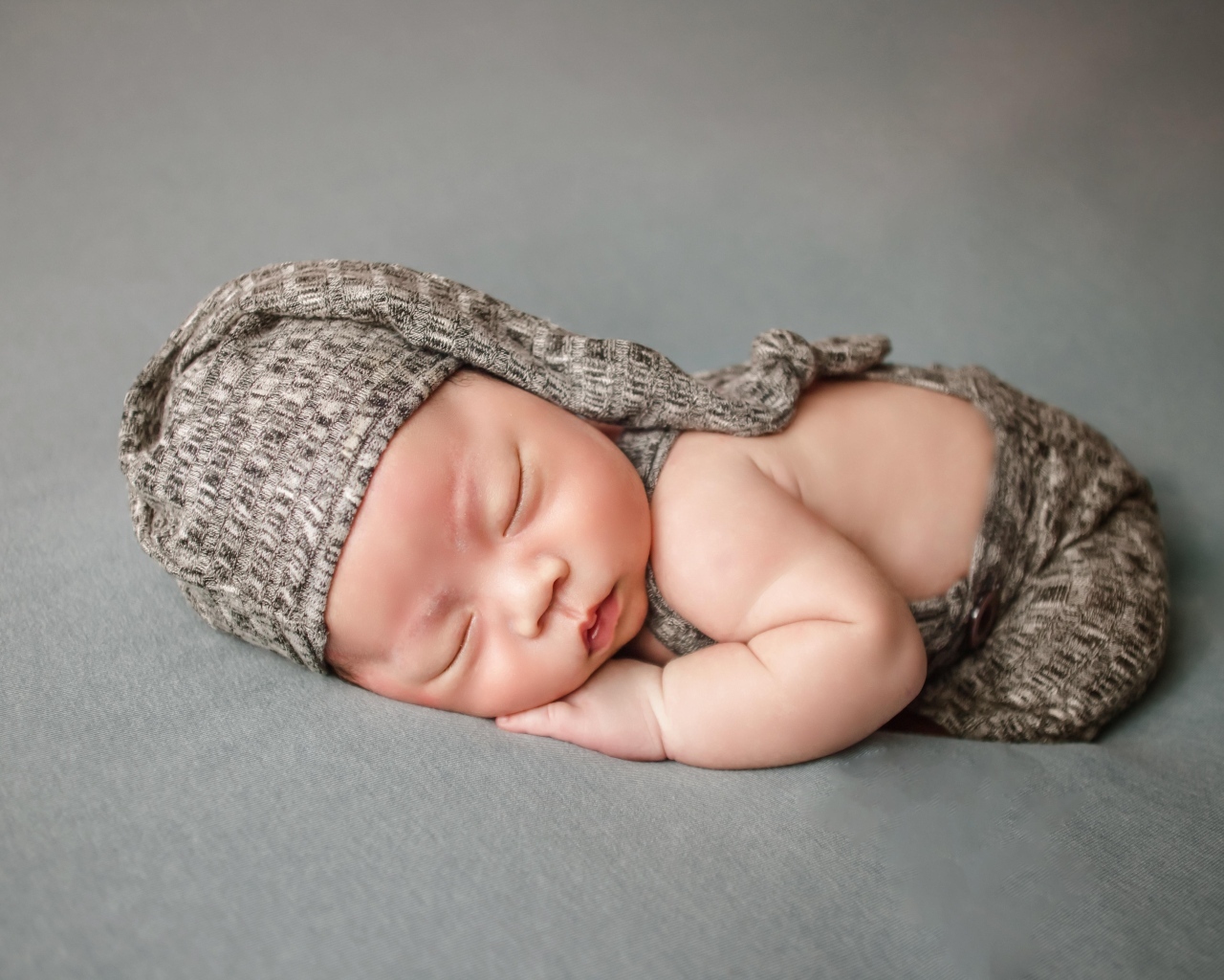 Ребенок спит в костюме на сером покрывале