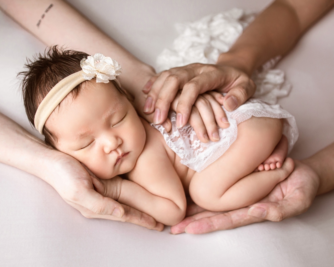 Руки родителей оберегают спящего малыша