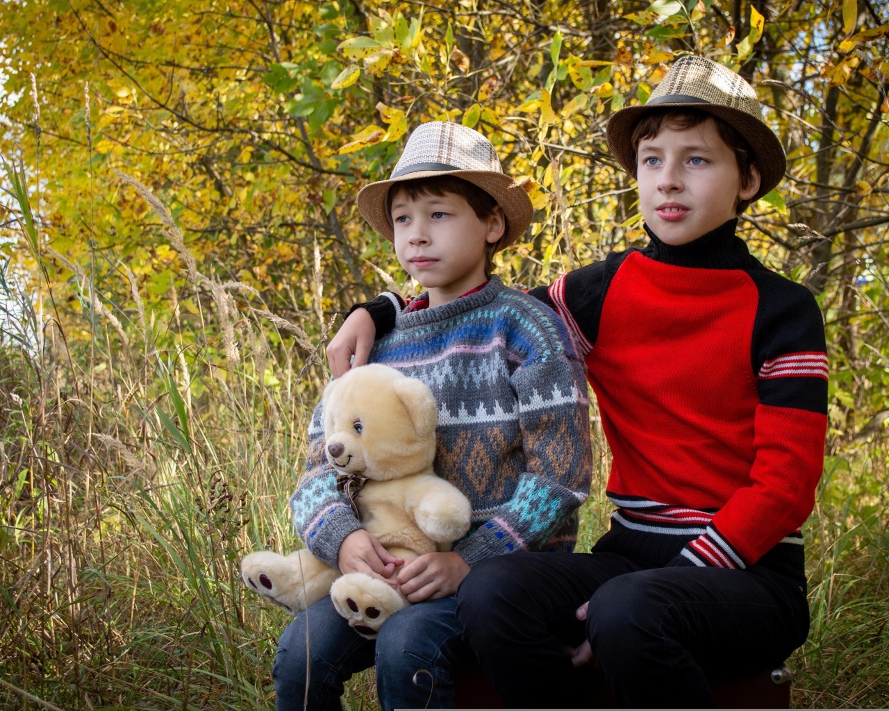 Два мальчика с игрушкой сидят у дерева