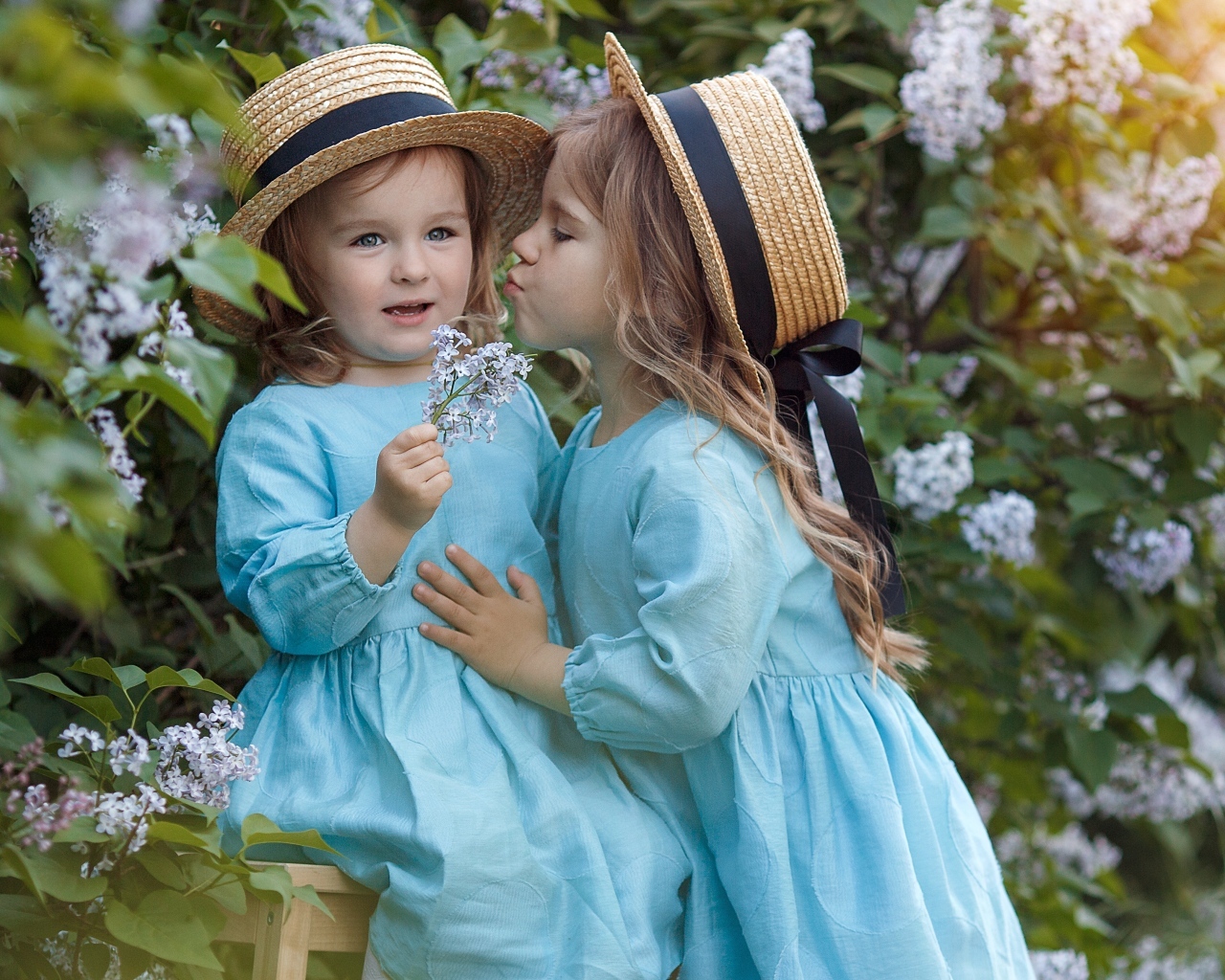 Две маленькие девочки в саду с сиренью