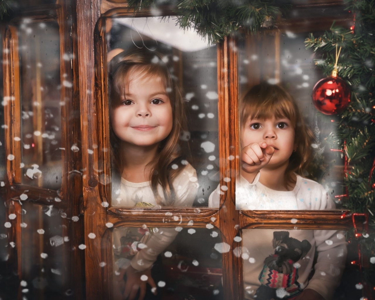Две маленькие девочки сидят у окна на Рождество