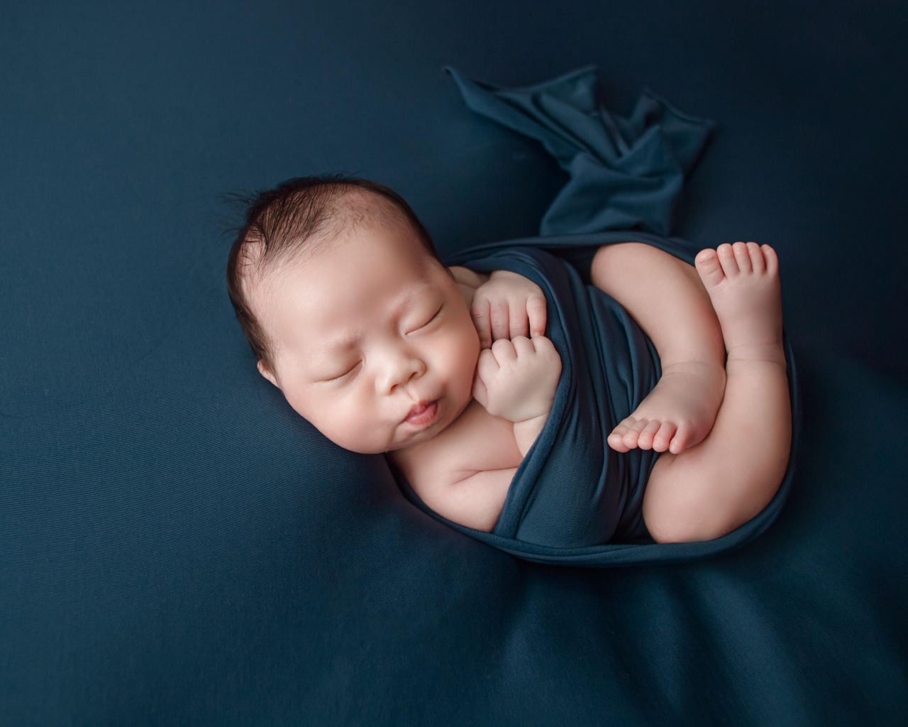 Новорожденный малыш в черном покрывале