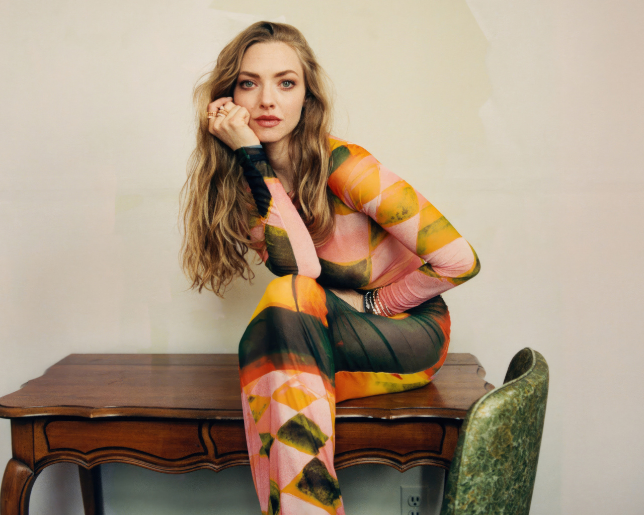 Актриса Аманда Сайфред в платье сидит на столе