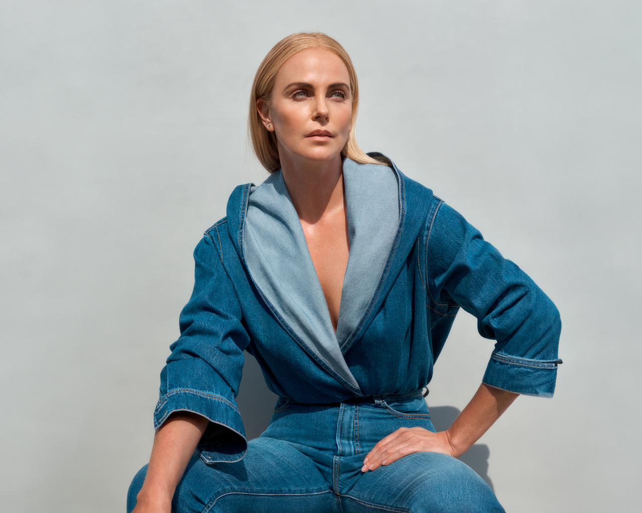 Актриса Шарлиз Терон в джинсовом костюме на сером фоне