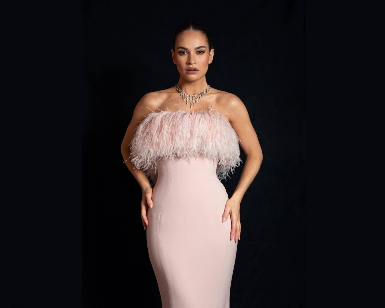 Актриса Лили Джеймс в розовом платье на черном фоне