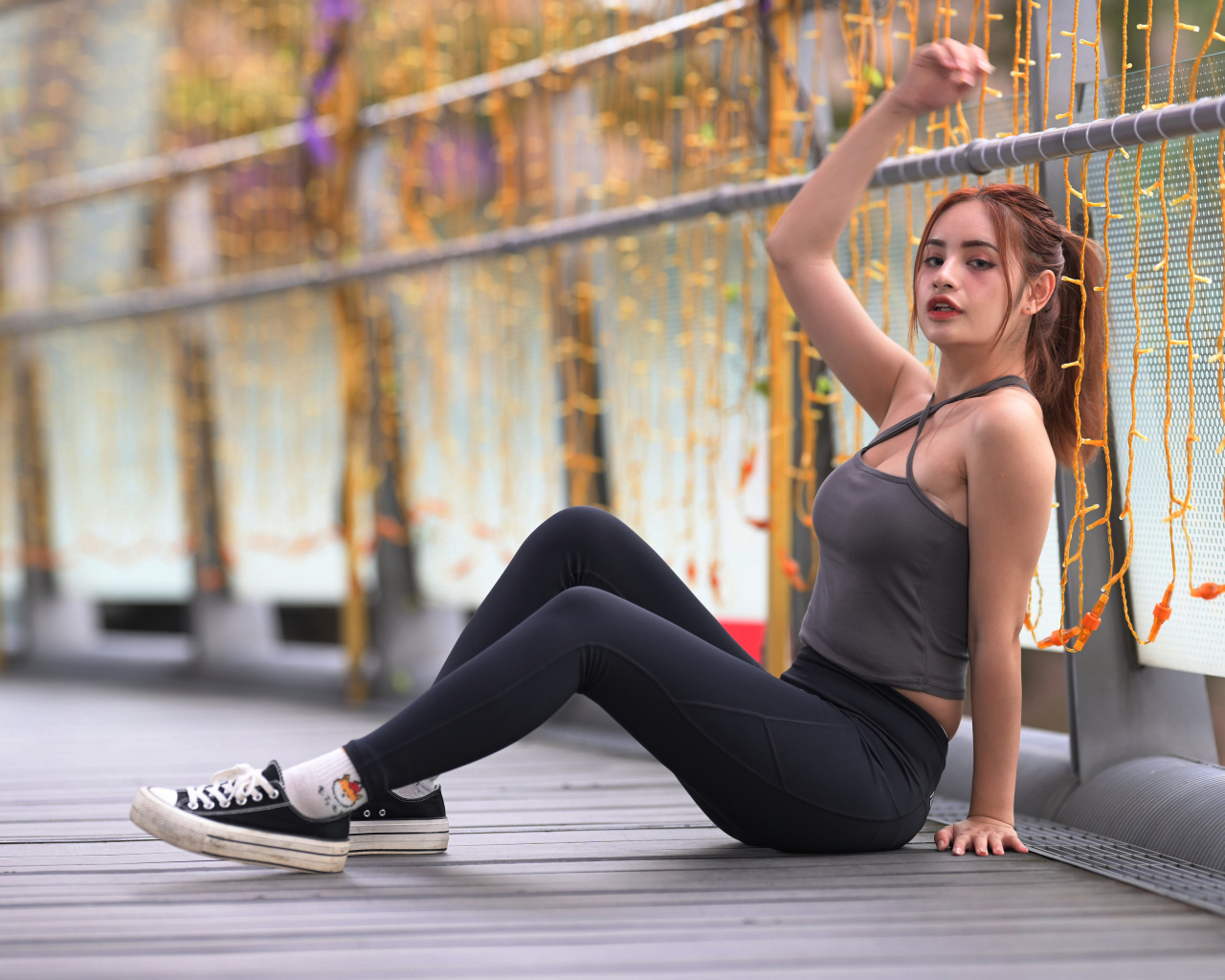 Спортивная девушка в костюме сидит на полу