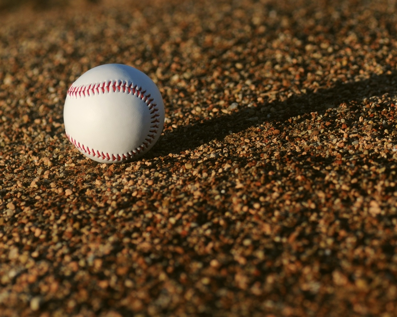 Бейсбольный мяч в лучах солнца на асфальте