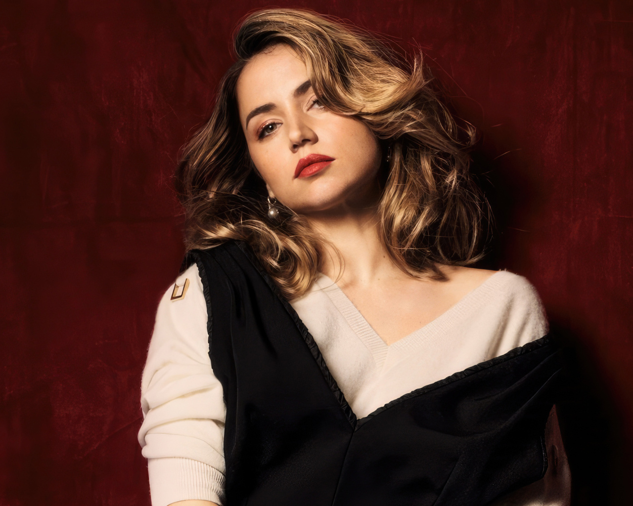 Милая актриса Ана де Армас стоит у красной стены