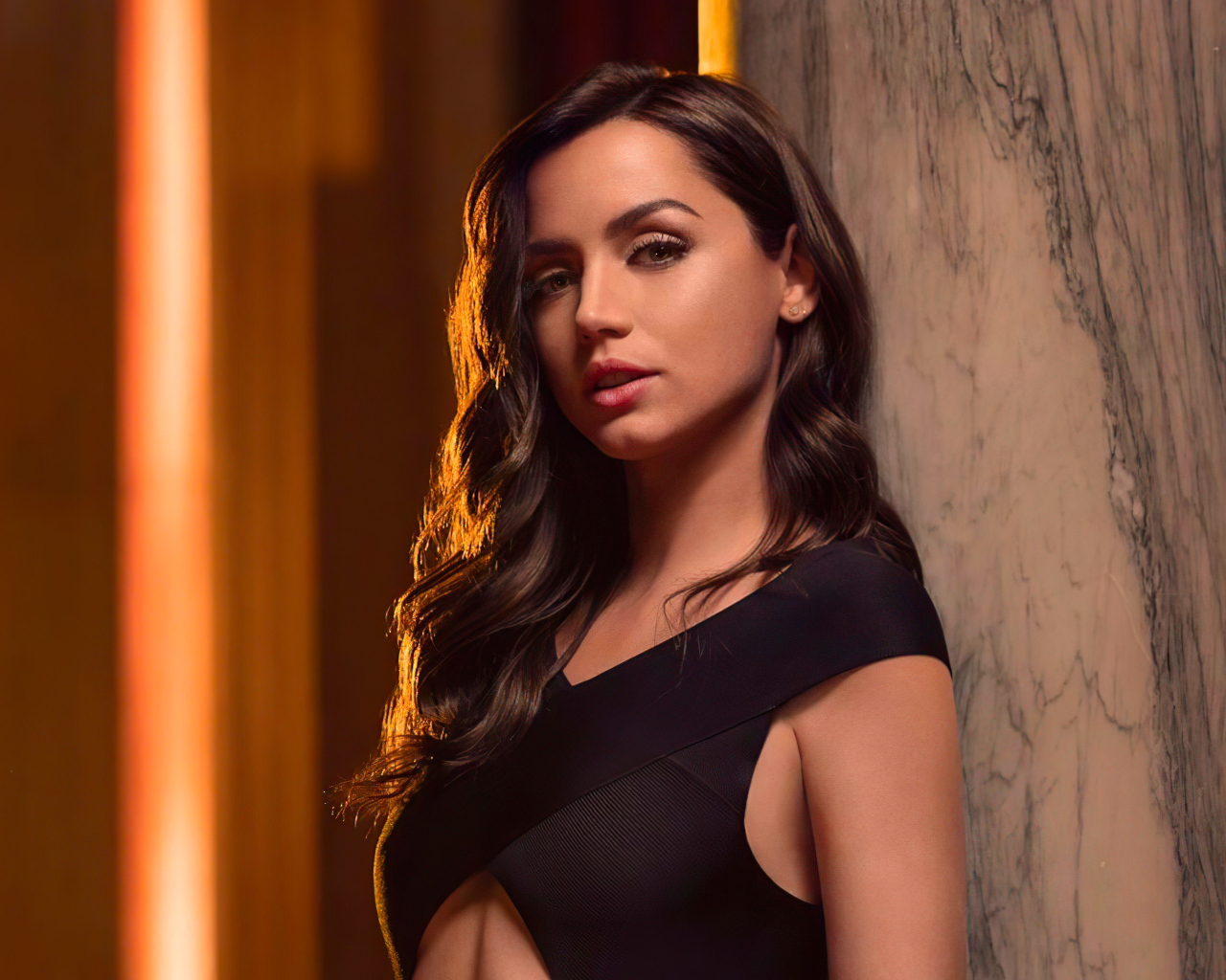 Длинноволосая актриса Ана де Армас стоит у стены