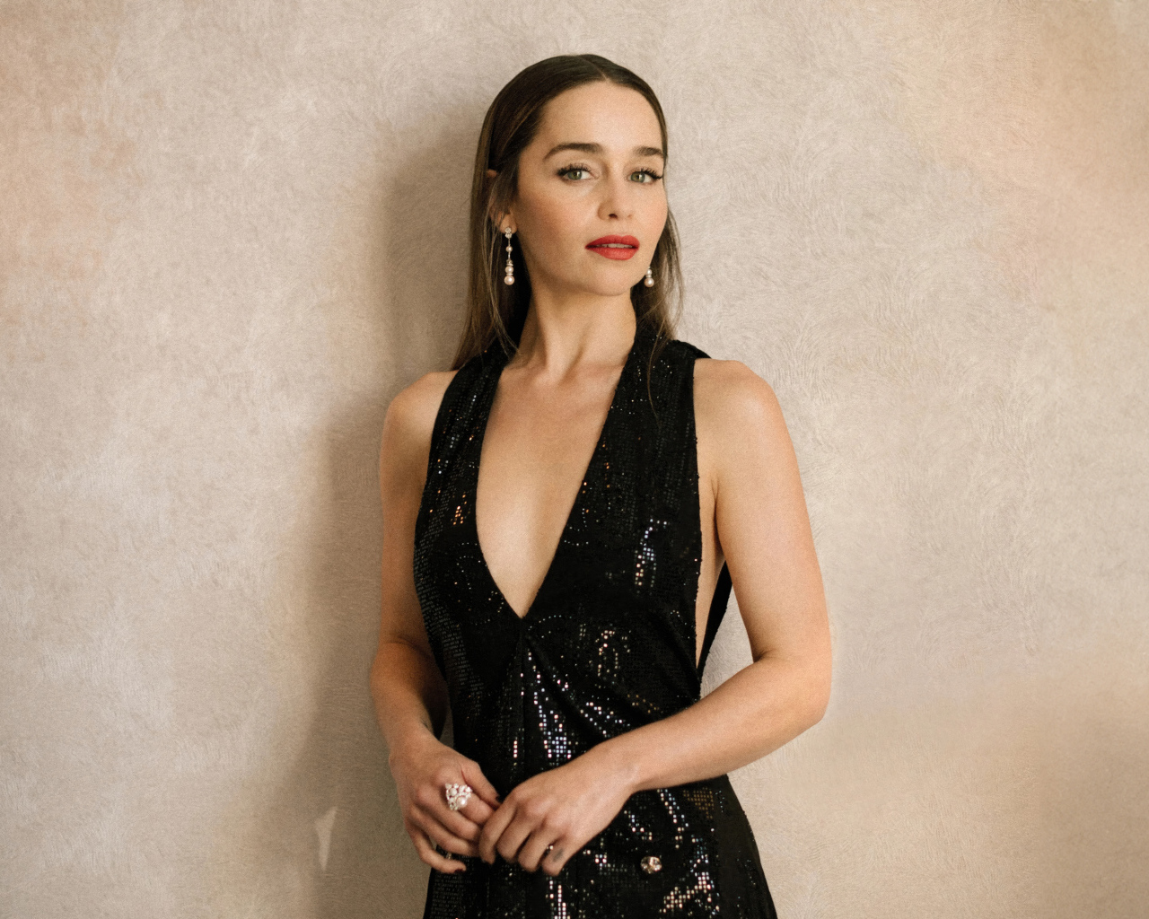 Популярная молодая актриса Эмилия Кларк в черном платье у стены