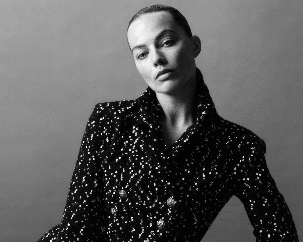 Грустная Марго Робби в блестящем пиджаке на сером фоне