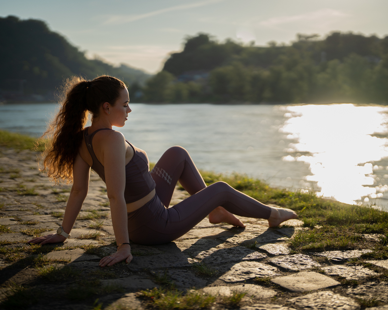 Спортивная девушка сидит на берегу реки