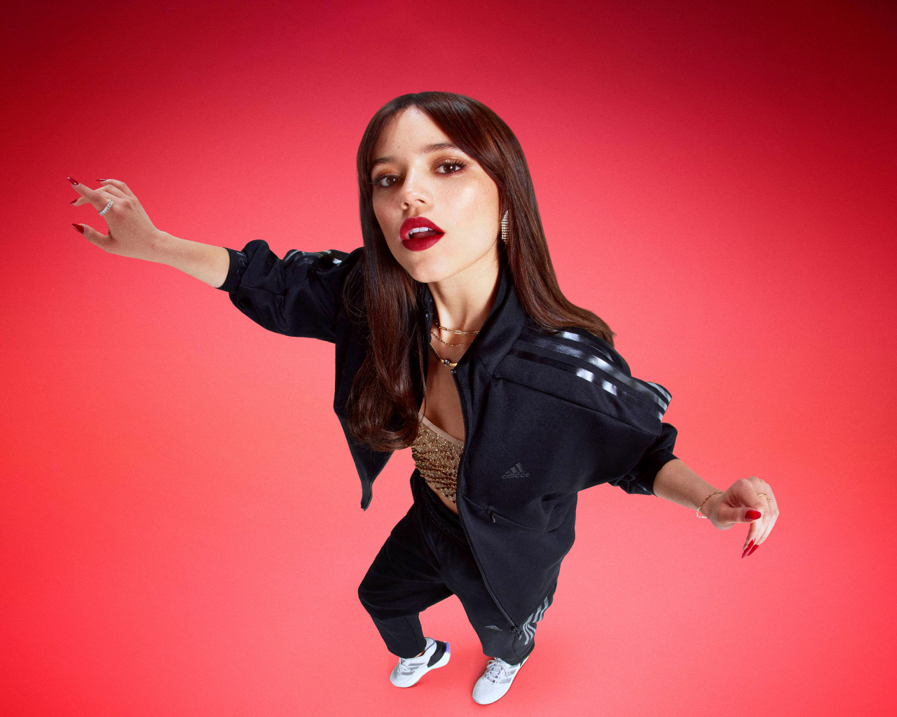 Молодая девушка актриса Дженна Ортега в спортивном костюме на красном фоне