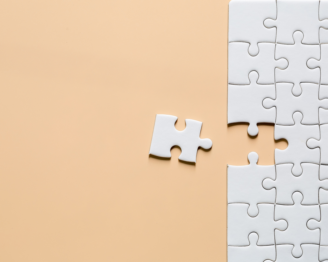 Белый пазл собирают на бежевом фоне