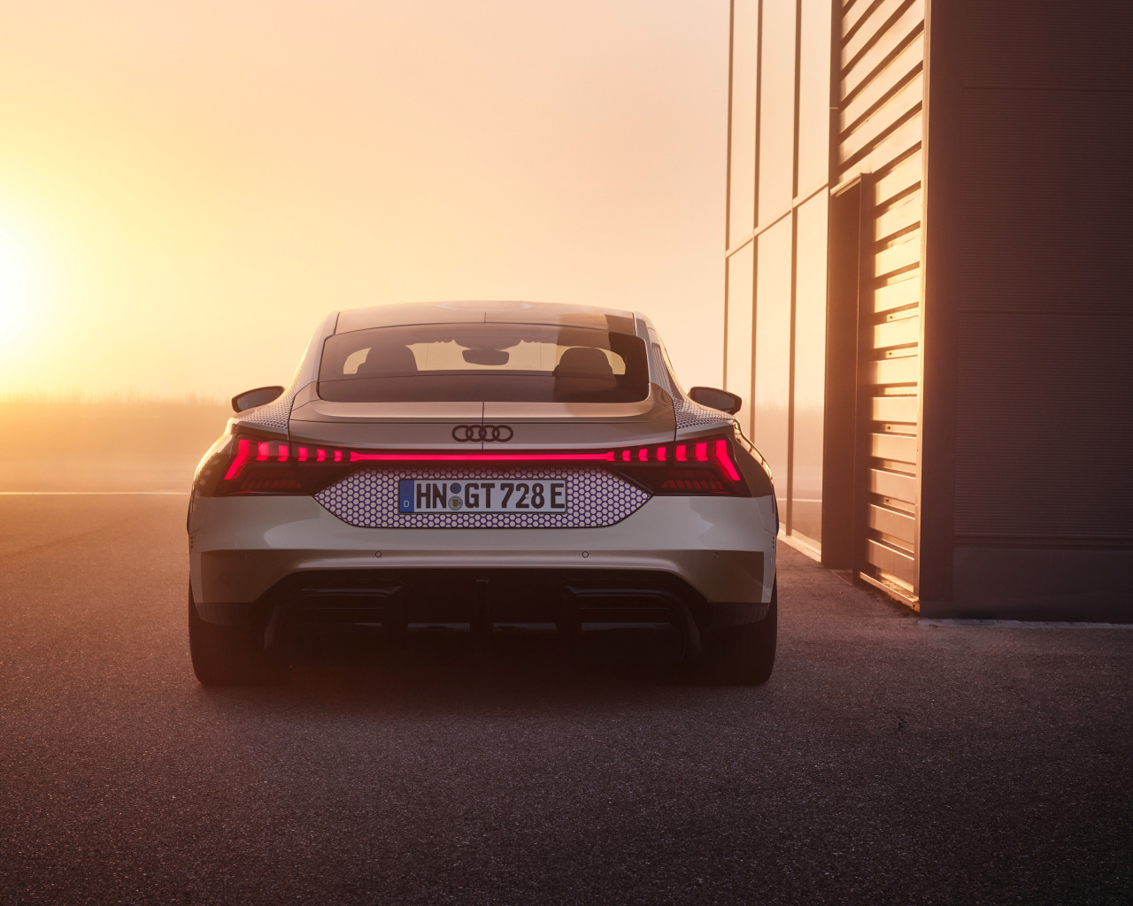 Вид сзади на автомобиль Audi RS E-Tron GT Prototype на фоне солнца
