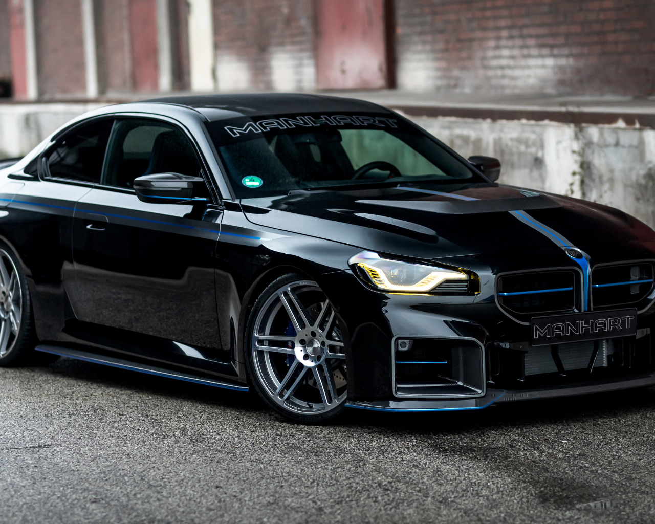 Черный автомобиль BMW M2 Manhart MH2 560 на сером фоне в городе