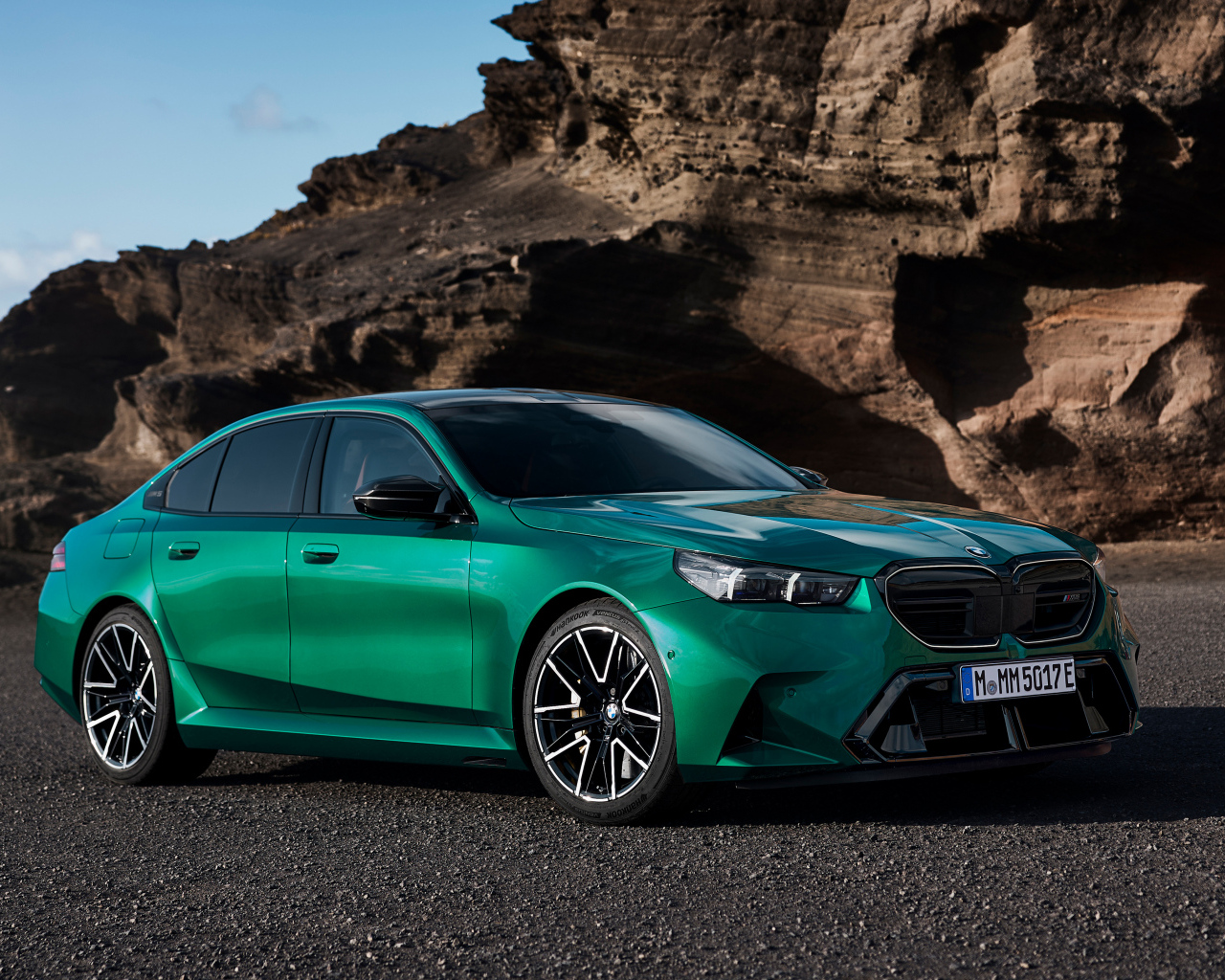 Зеленый автомобиль BMW M5 2024 года на фоне гор