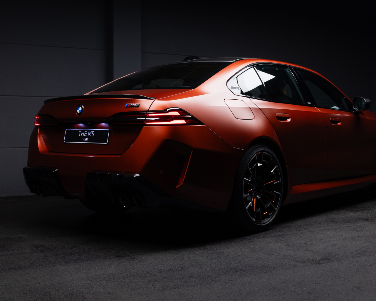 Вид сзади на красный автомобиль BMW M5 2025 года