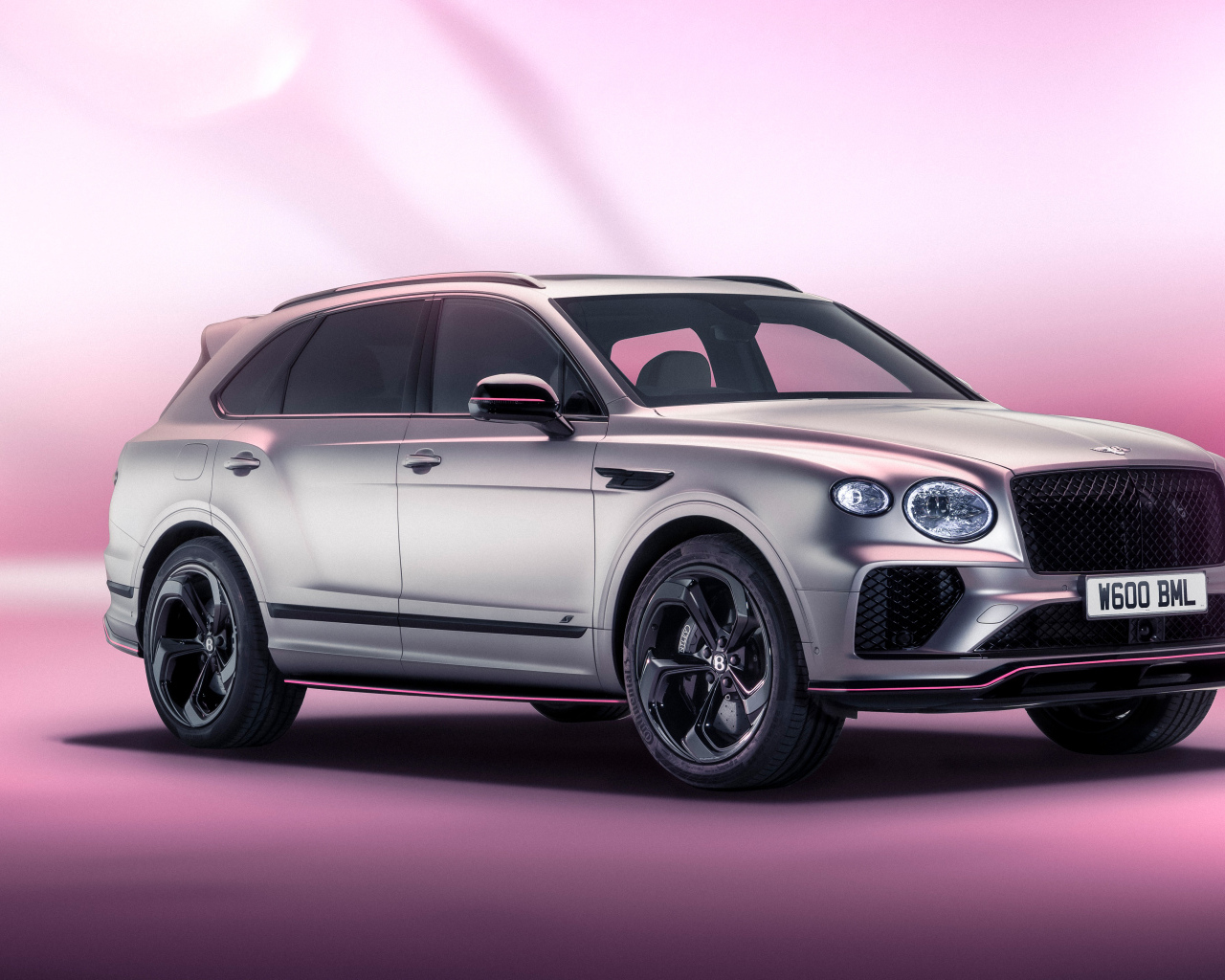 Серебристый автомобиль Bentley Bentayga V8 S Curated By Mulliner 2024 года на розовом фоне