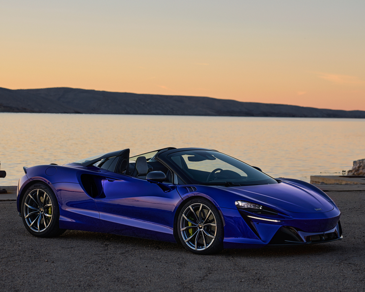 Синий быстрый автомобиль McLaren Artura Spider у воды
