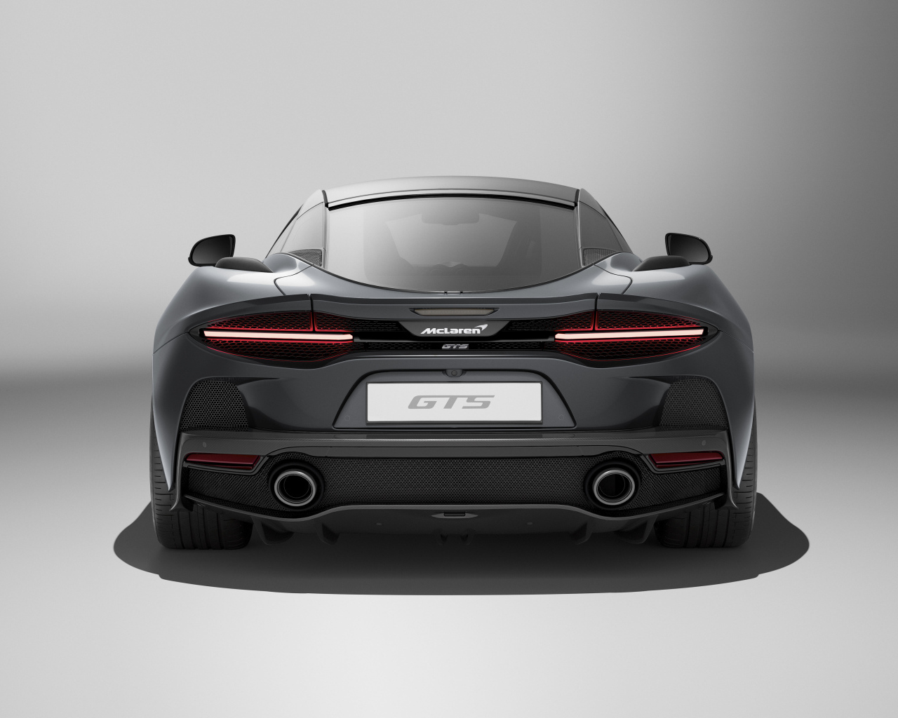 Вид сзади на автомобиль McLaren GTS на сером фоне