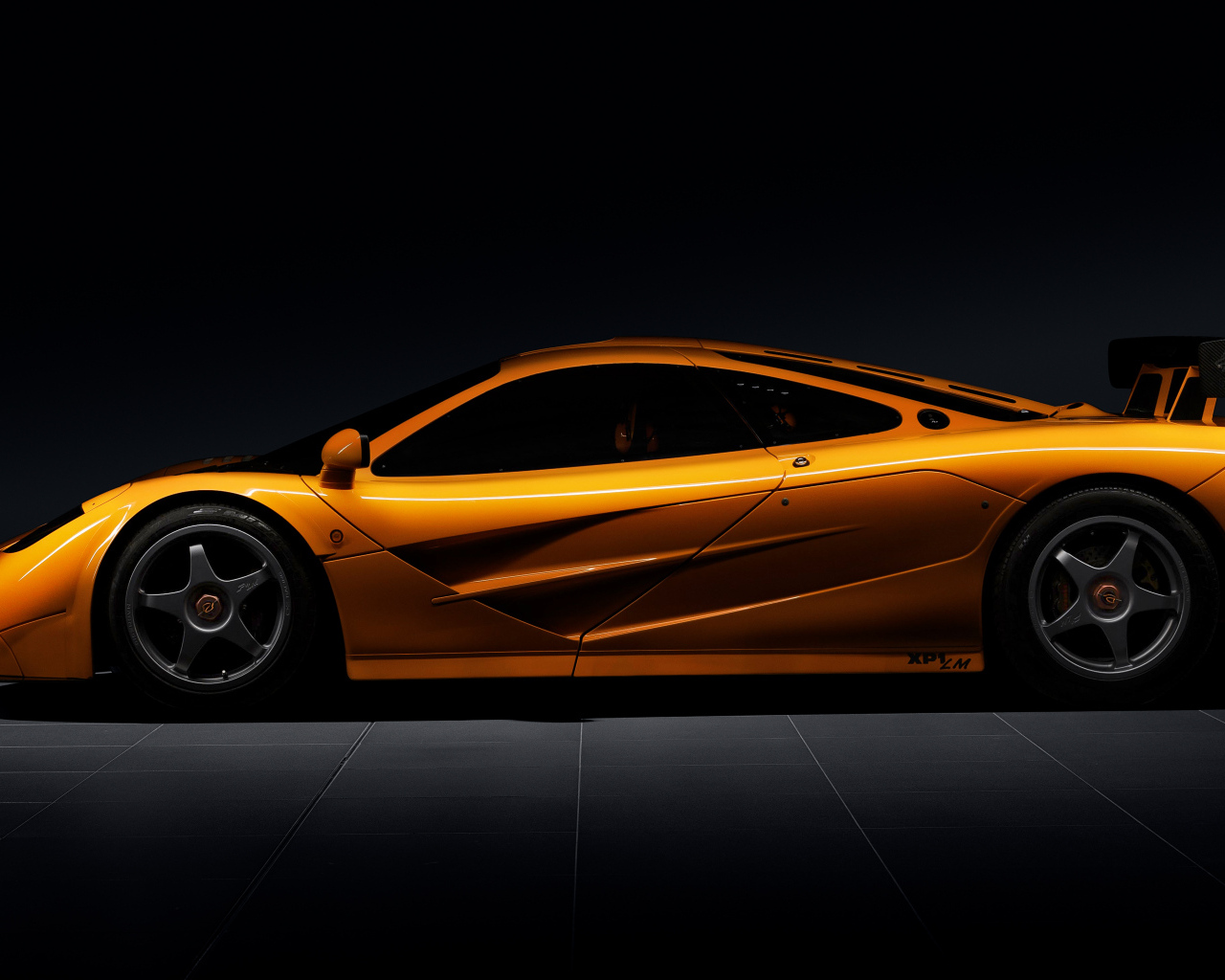 Вид сбоку на оранжевый автомобиль  McLaren F1 LM